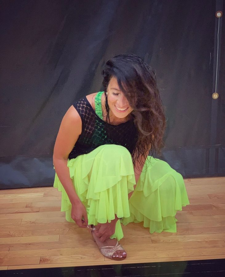Romi, the instructor, smiling and adjusting her heels before class